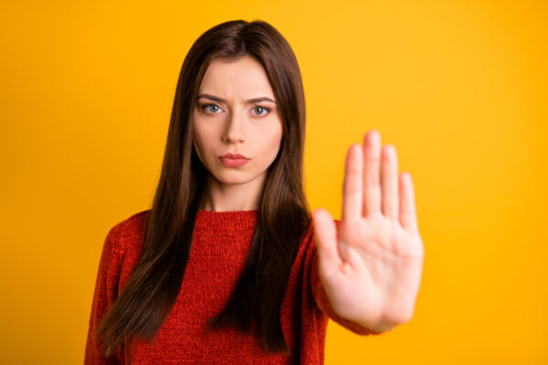 体の前に手を出して止める女性